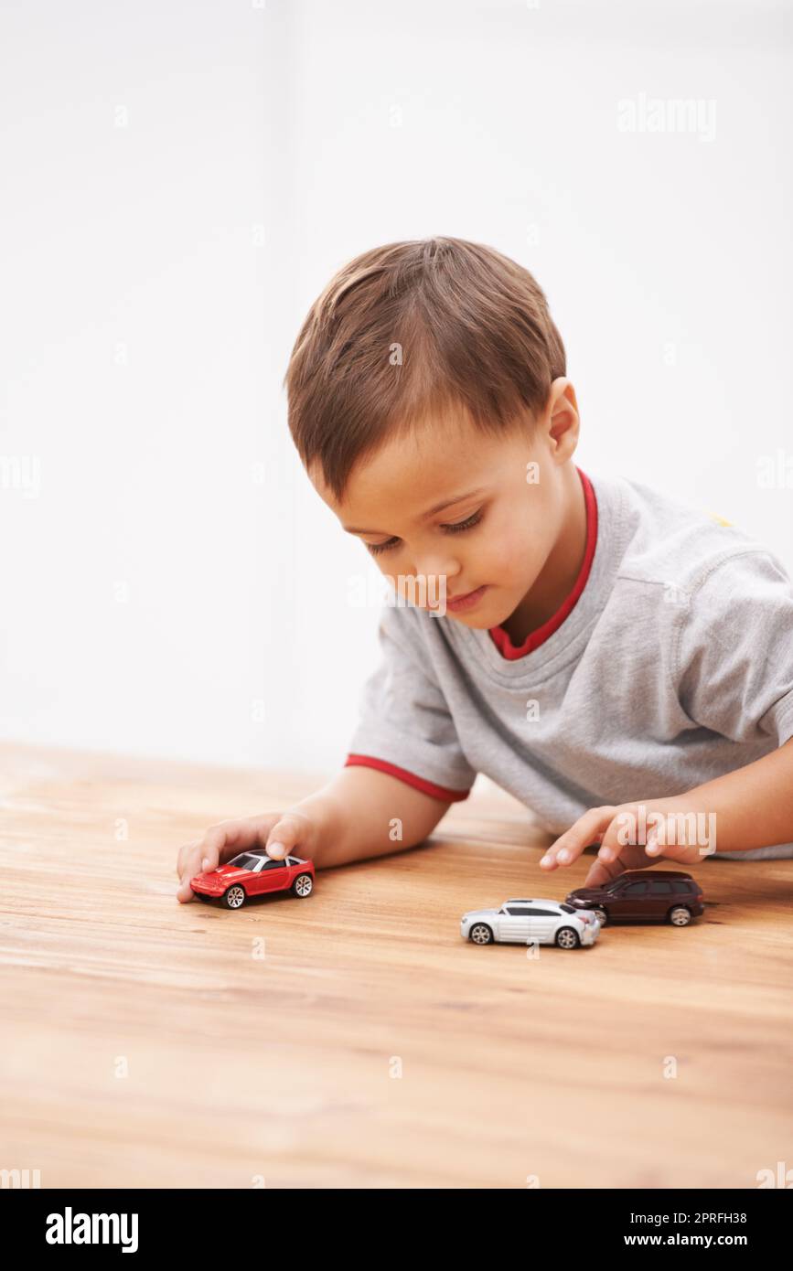 Boys and their toys. a cute young boy playing with toy cars Stock Photo ...