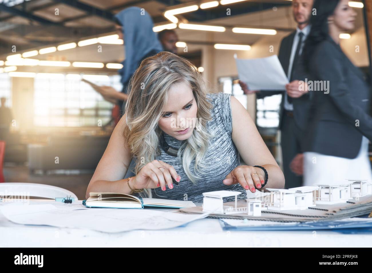 Working to bring her vision to life. a team of successful businesspeople working with a scale model of a building in their office. Stock Photo