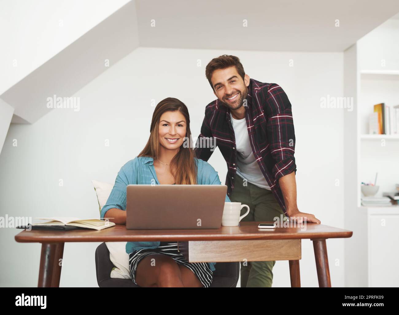 Why would we want to work anywhere else. Portrait of a happy couple of entrepreneurs working together from their home office. Stock Photo