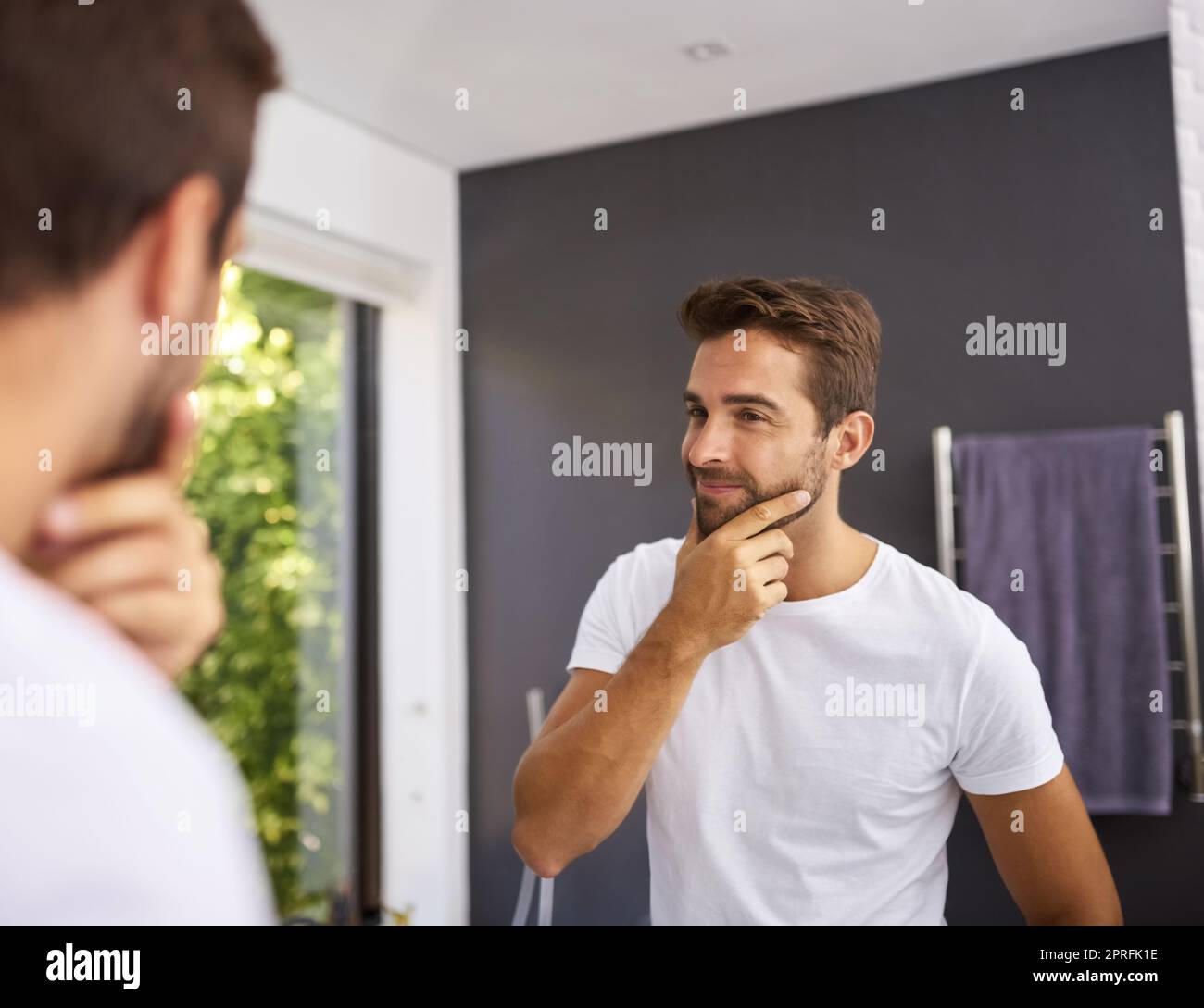 To shave or not to shave thats the question. a handsome man rubbing his