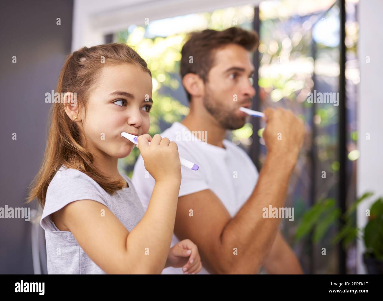 1, 2, 3, Together. a handsome Dad and his daughter brushing their teeth in the bathroom. Stock Photo