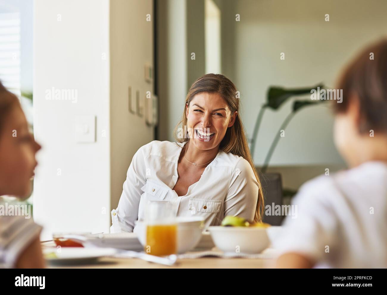 Her kids have the funniest stories to tell. a mother having breakfast with her children at home. Stock Photo