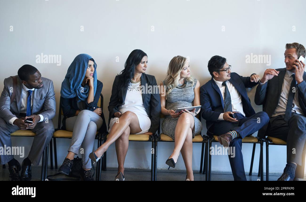 These other candidates are no competition. a group of job applicants looking annoyed at a man answering his phone while they wait. Stock Photo