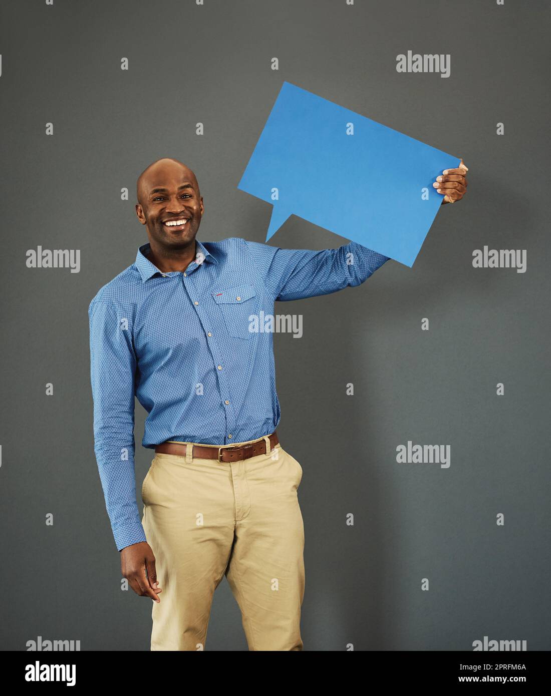 Smiling, african american male voter holding a copyspace board sign on public opinion message. Casual and positive man holding a social media speech bubble or communication icon for news poll idea Stock Photo