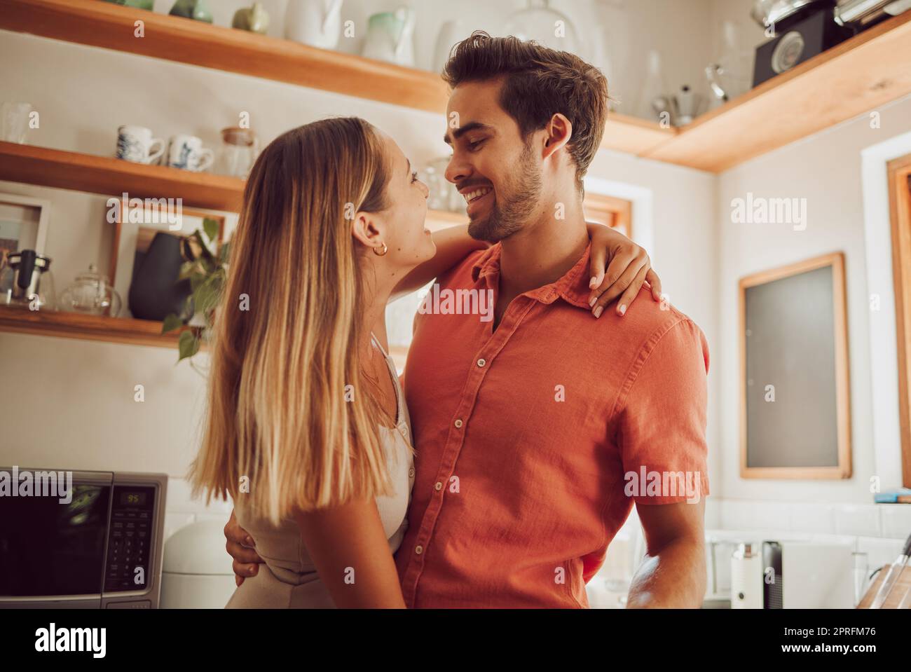 Romance, happy and love couple hugging, smile and bonding in kitchen. Romantic boyfriend and girlfriend embracing, enjoying their relationship and being carefree together. Stock Photo