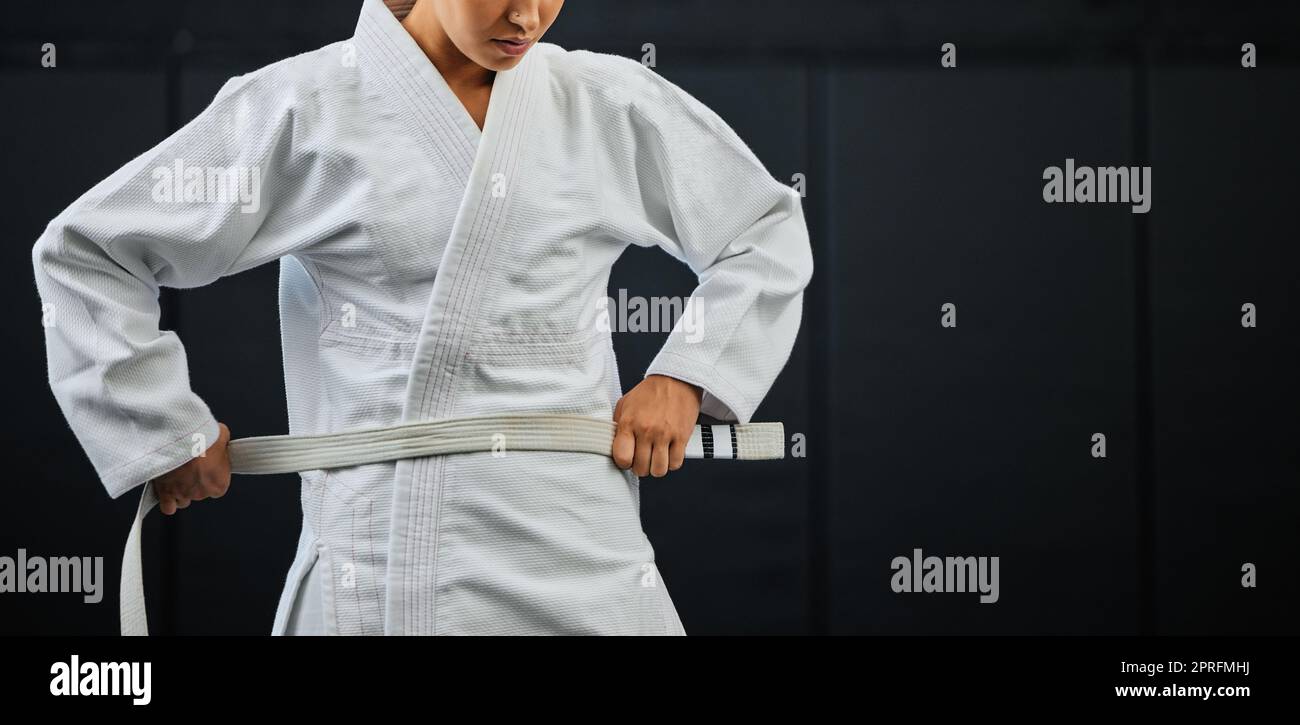 .Beginner, karate and student getting ready for the first day of self defense training against a dark background in a dojo. Determined learner in motivation for fighting lessons in the martial arts. Stock Photo