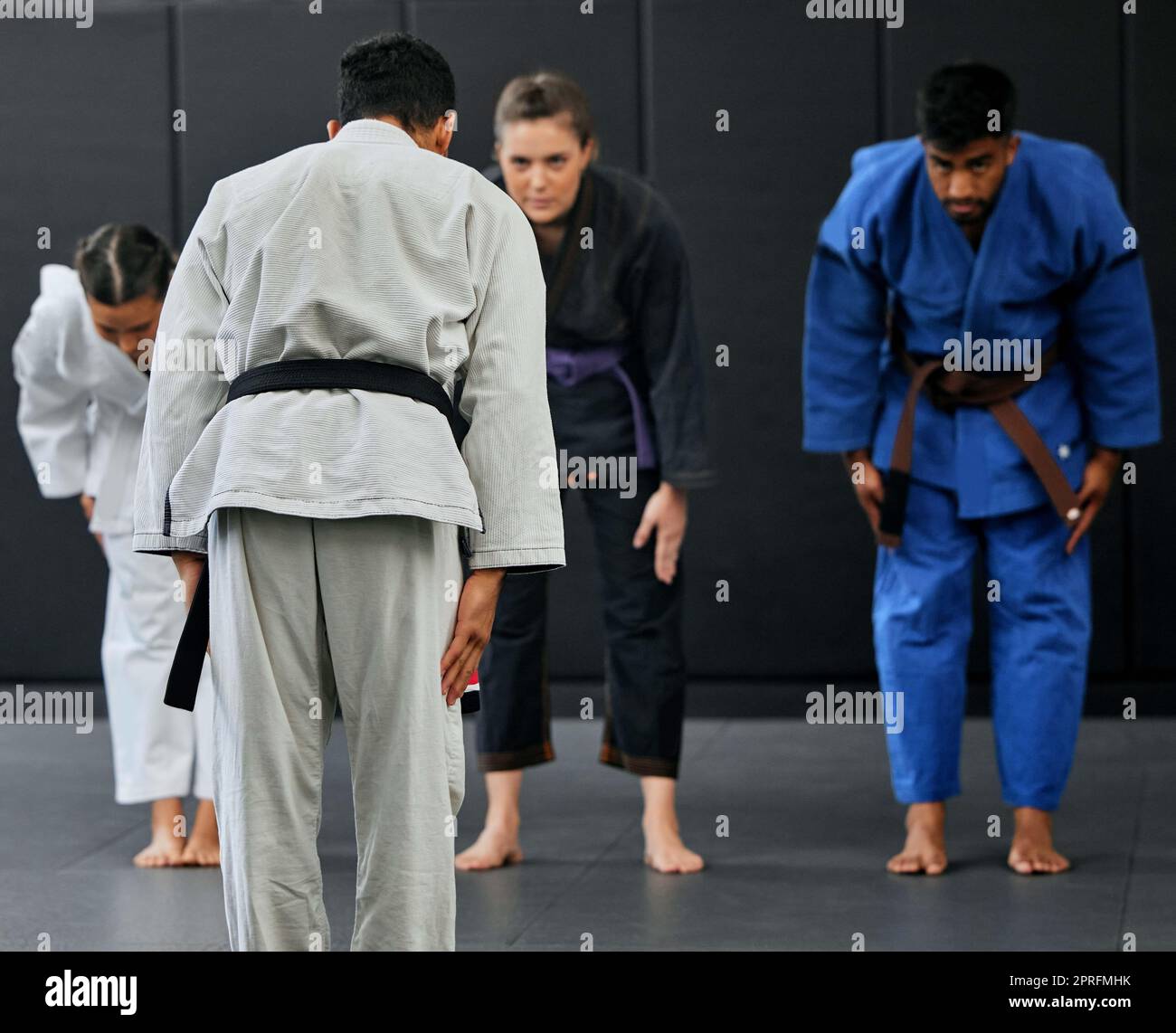 Fitness, strength and respect between karate trainer leading a class, bow and greeting martial arts student at a dojo or studio. Diverse group training and learning self defense and endurance skills Stock Photo