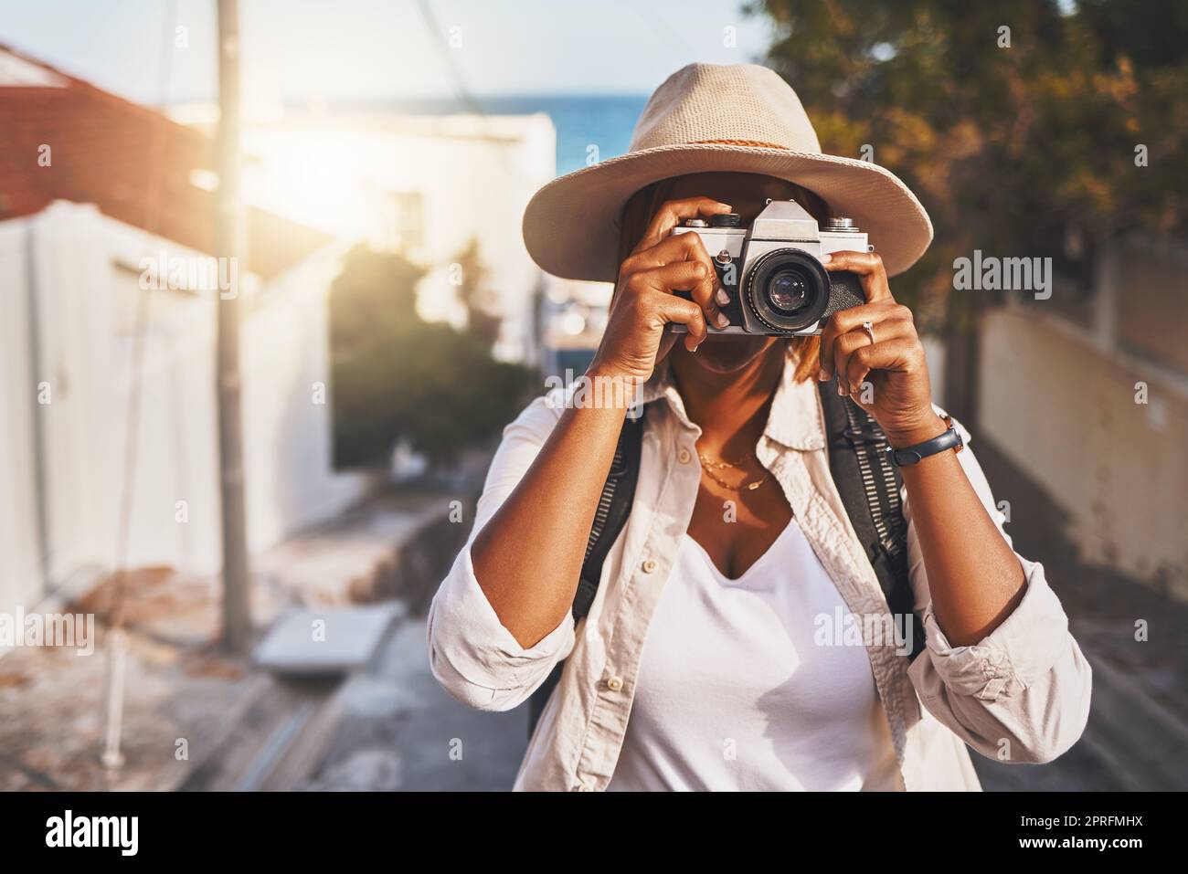 Photographer, travel or tourist taking pictures or photos outdoors in a new town. Traveler using a camera while on a trip at a vacation or holiday location on a sunny day doing a photoshoot Stock Photo