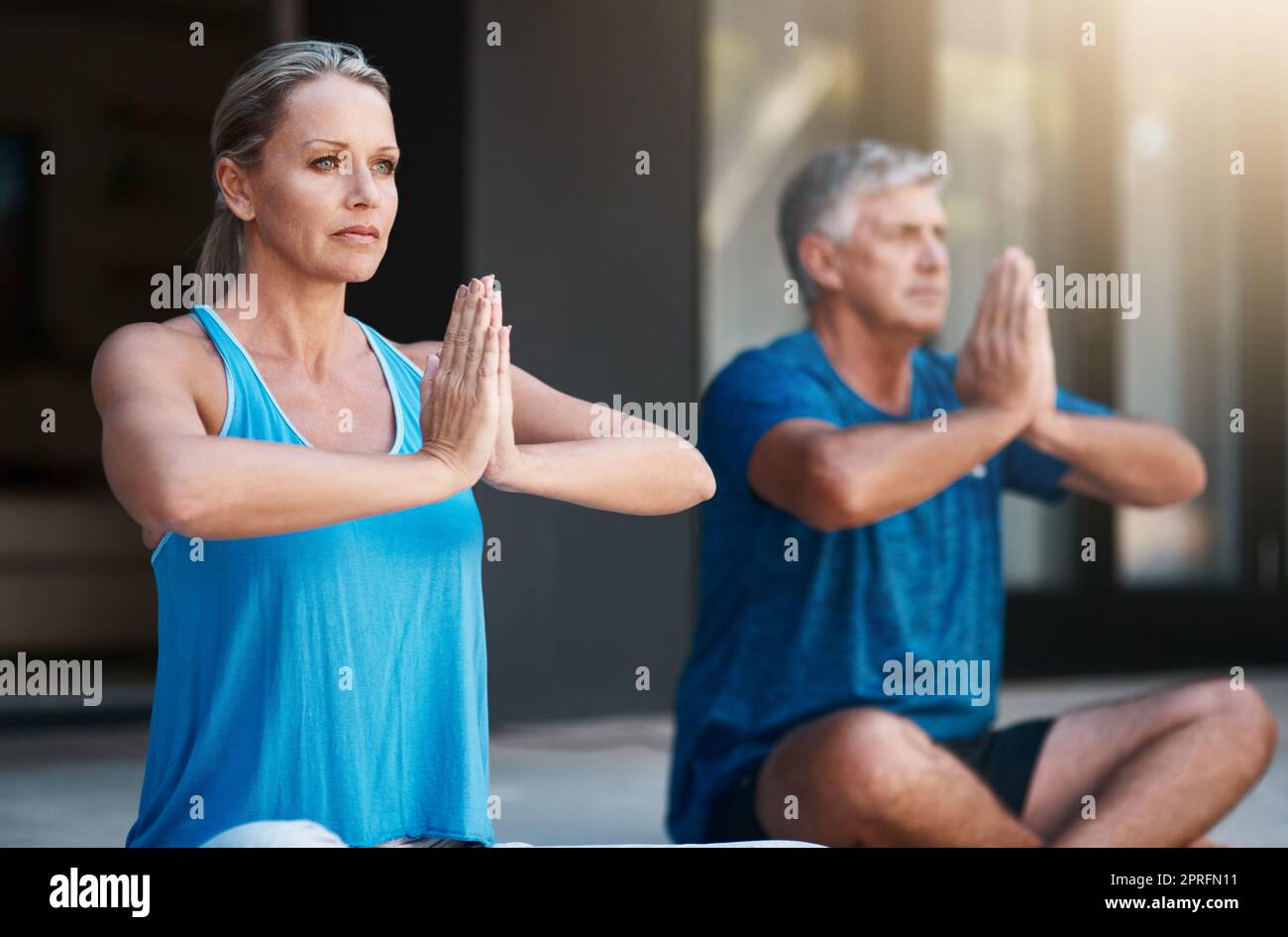 Being at peace with our own selves makes everything easier. a mature and happy couple meditating outside of their home in the morning. Stock Photo
