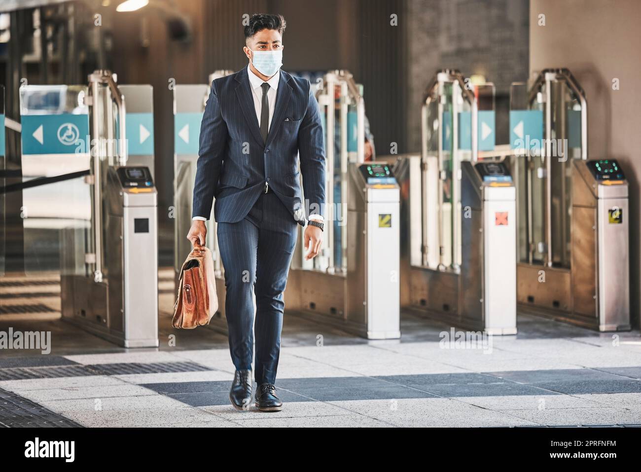 Covid, health and safety on public transport, a businessman walking in a bus or train station in a business suit and face mask. Career, travel and an office worker on his morning journey in the city. Stock Photo