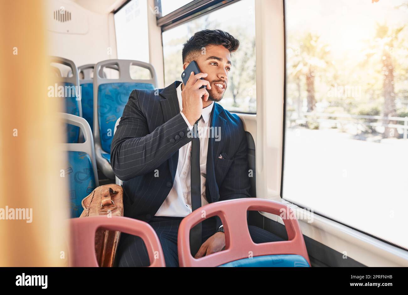 Phone, travel or communication with a business man talking and networking on a bus, public transport and commuting in a city. 5g mobile technology with a young worker having a conversation on a call Stock Photo