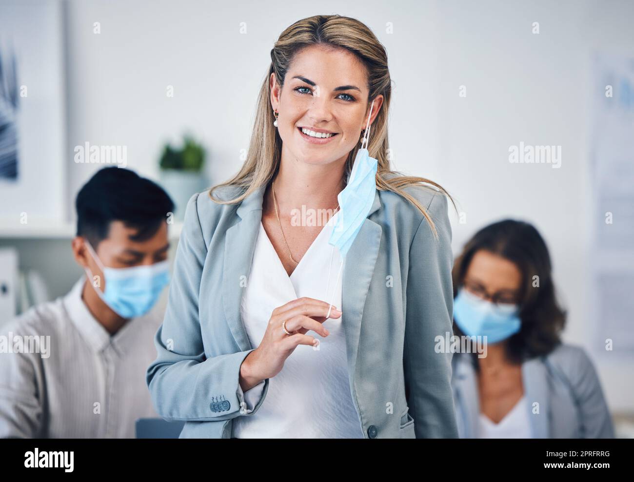 Portrait of a business woman in her office with a face mask and her team during covid pandemic. Corporate, creative and professional manager working on a group project in the company conference room. Stock Photo