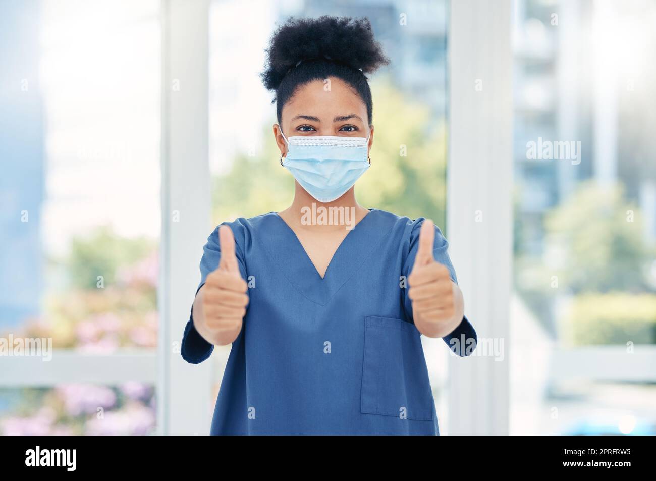 Thumbs up nurse, doctor and surgeon in covid hospital, clinic and surgery for healthcare success, trust and support. Portrait of medical worker with hand emoji for motivation, agreement and good news Stock Photo