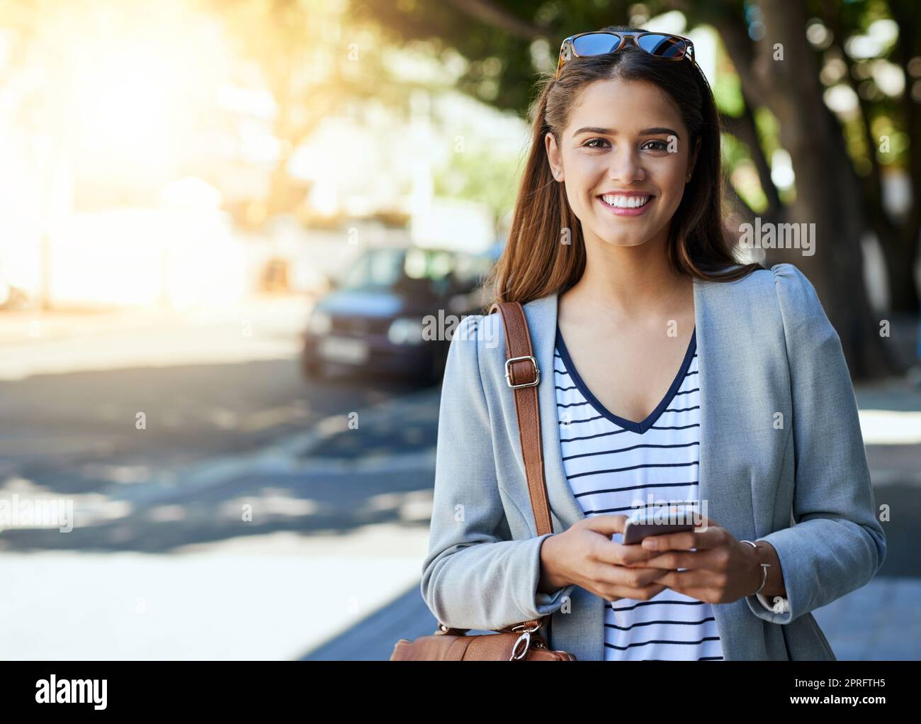 Connected on the move. Cropped portrait of an attractive young woman using her cellphone while commuting to work. Stock Photo