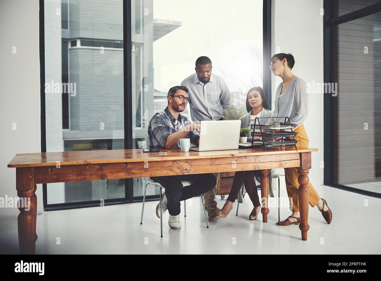 Teamwork makes the dream work. Full length shot of a group of businesspeople gathered around a laptop in their office. Stock Photo