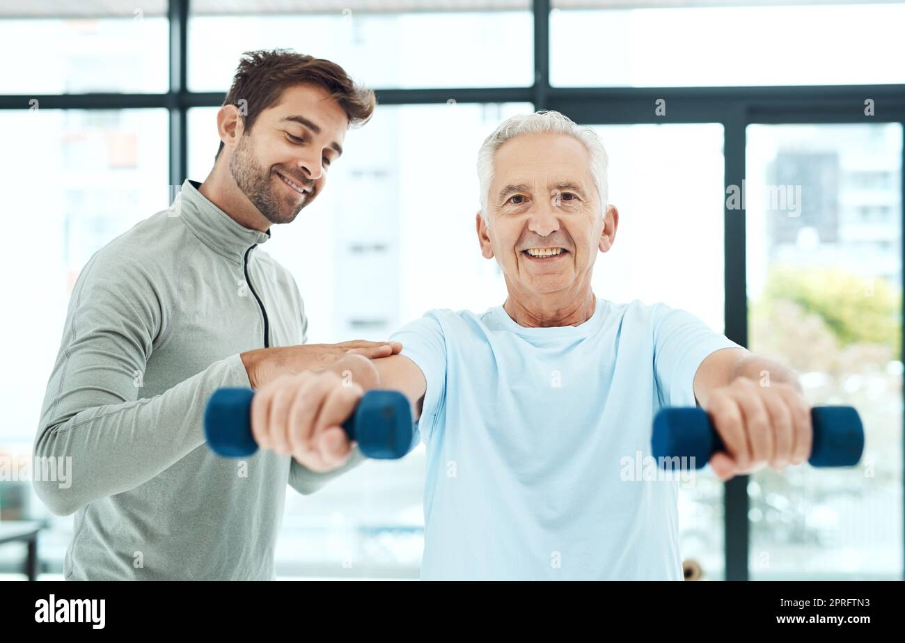 Can you feel that. a friendly physiotherapist helping his senior patient work out with weights. Stock Photo