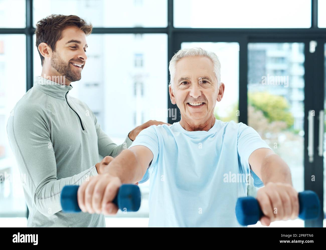 I love my physio sessions. a friendly physiotherapist helping his senior patient work out with weights. Stock Photo