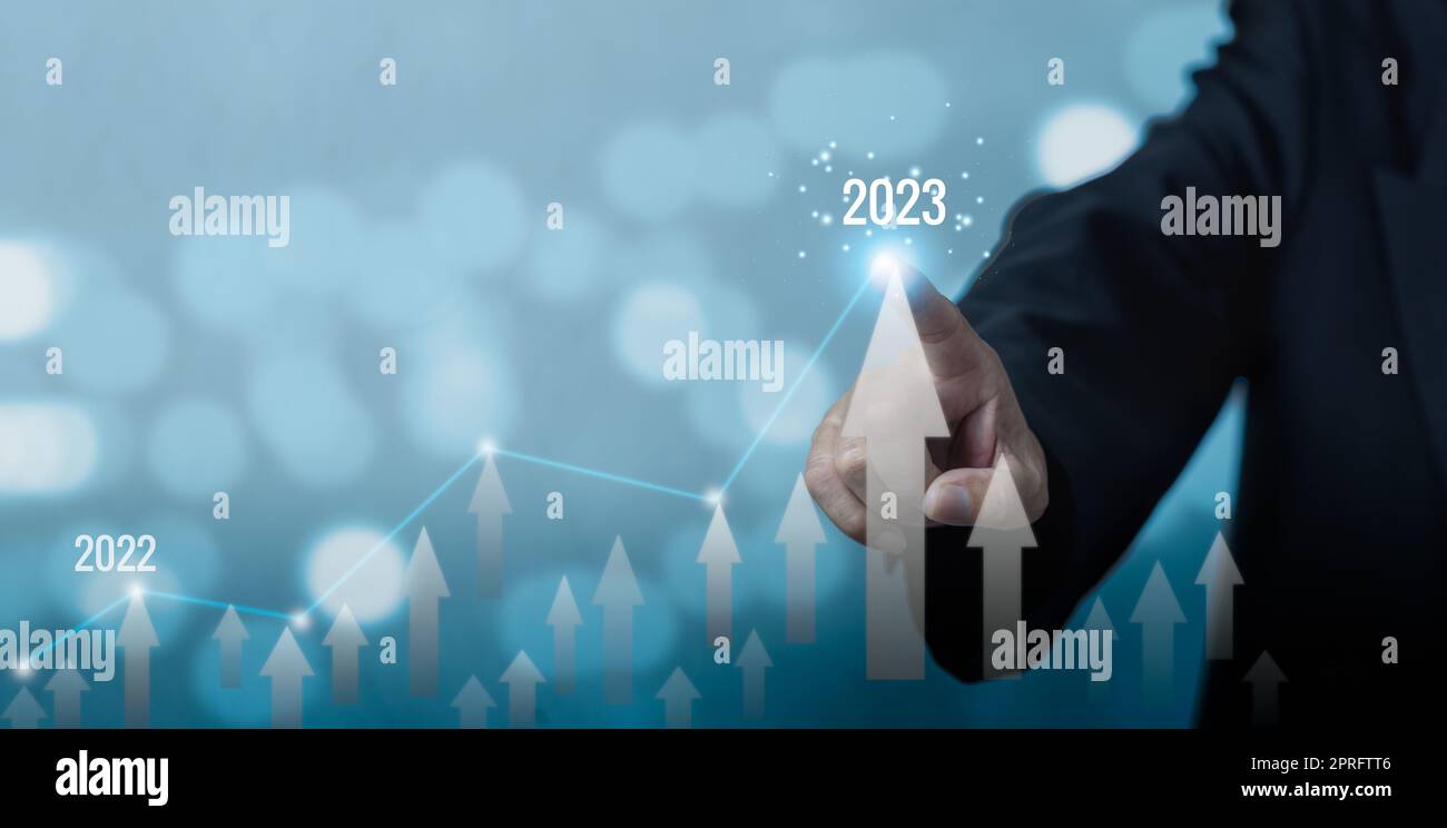 Businessman touch arrow and 2023 currency copy space background.Business finance growth success process investment economic market concept. Stock Photo