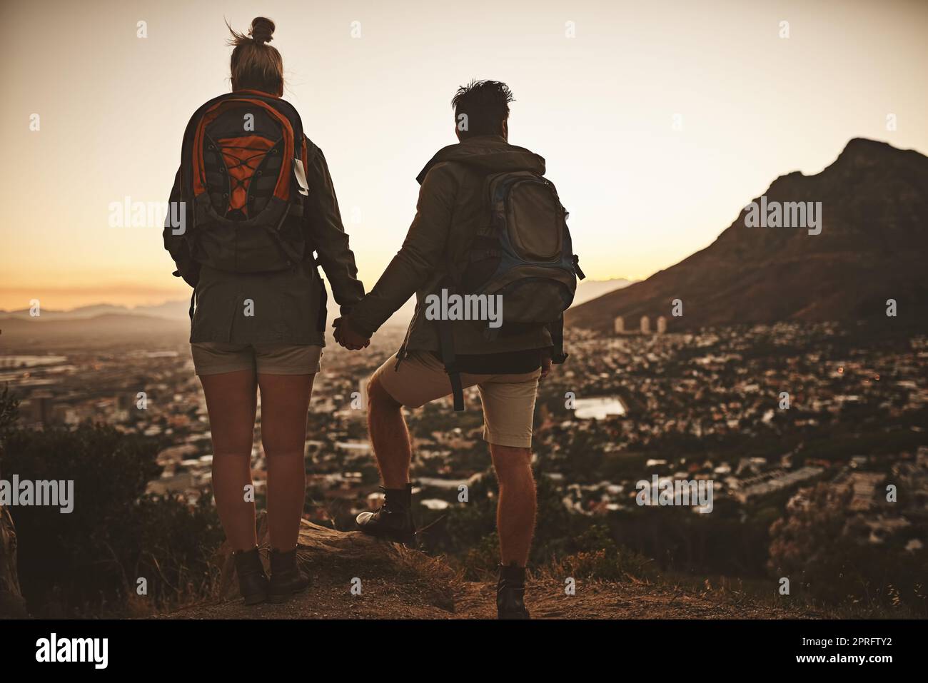 They share the same thirst for adventure. Rearview shot of a couple admiring the view from a mountain top. Stock Photo
