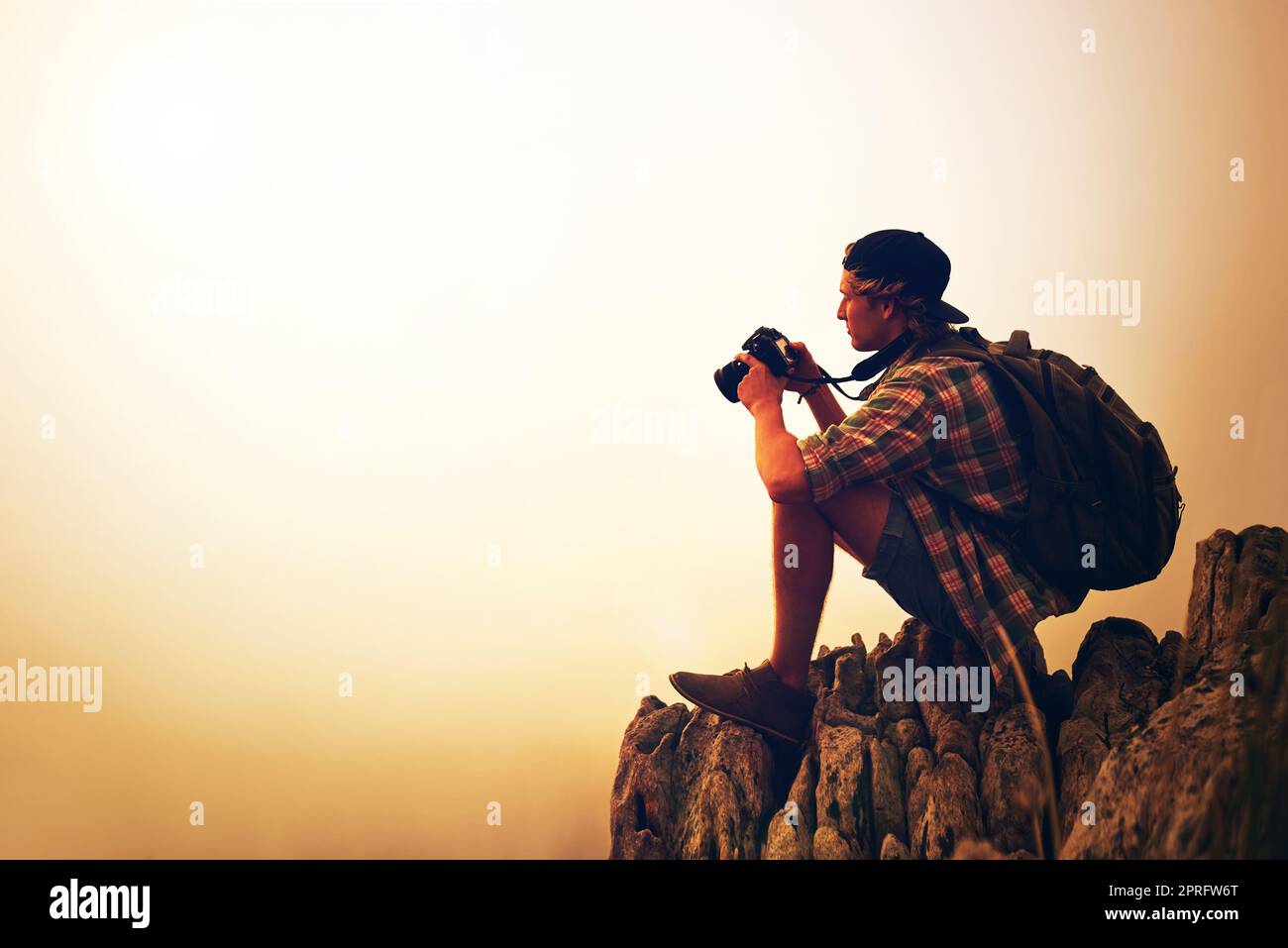 Capturing the world as he sees it. a young photographer taking a picture of a foggy landscape from the top of a mountain. Stock Photo