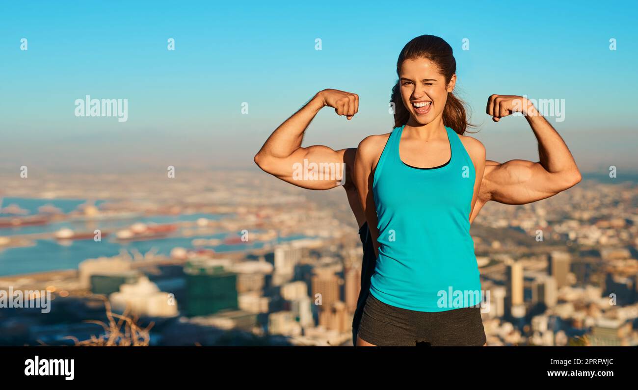 Showing off her guns. Cropped portrait of a young woman standing in front of her boyfriend whos flexing his muscles. Stock Photo