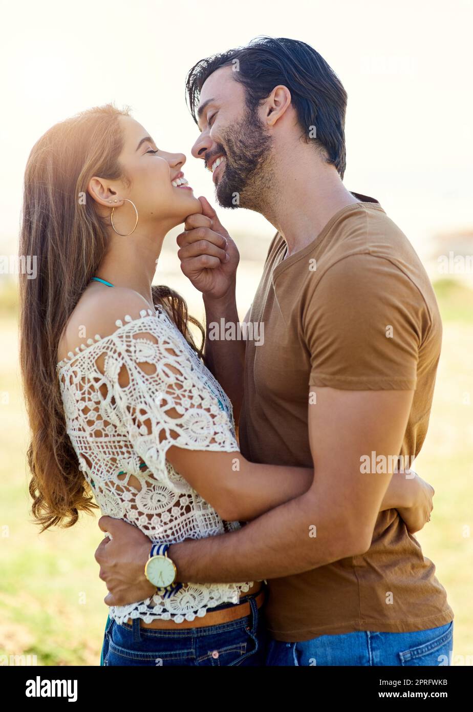 I got you babe. a smiling young couple embracing while enjoying a day together at the park. Stock Photo