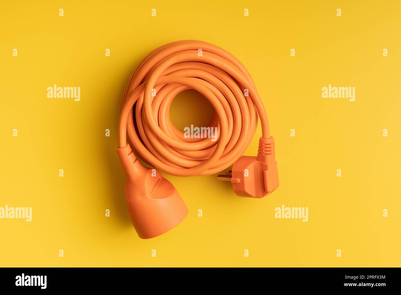 Orange extension Power Cord on yellow background. Stock Photo