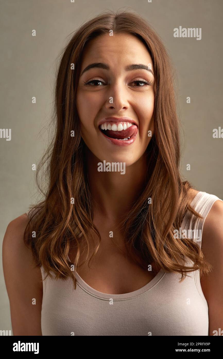 Pretty and playful. Studio portrait of an attractive young woman making a face against a brown background. Stock Photo