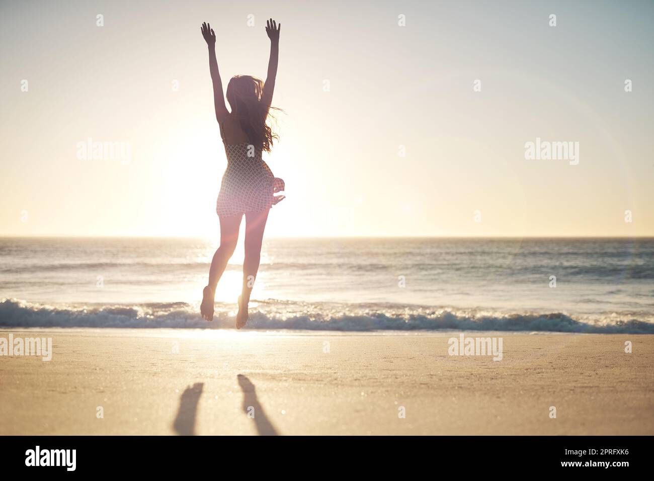 Jump for joy. a young woman jumping into mid air at the beach. Stock Photo