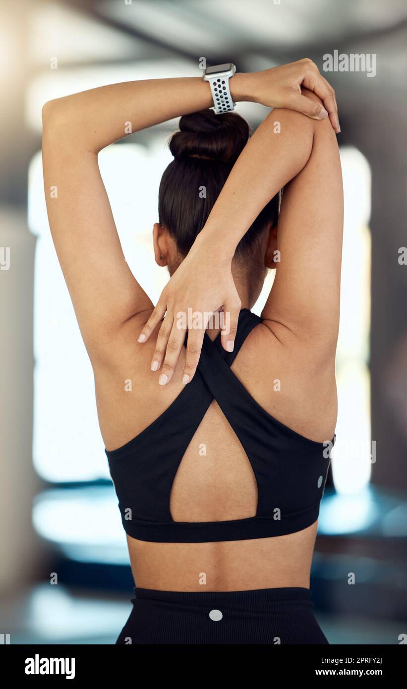 Fitness, back view or black woman in gym stretching to warm up body or  relax arm muscles in workout exercise. Wellness, flexible or healthy sports  girl training or exercising with focus or