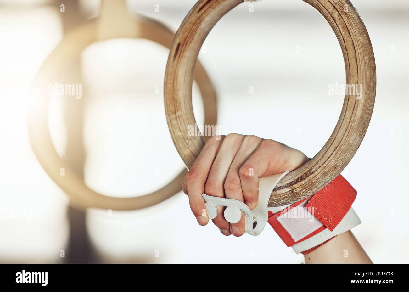 Hands of man gymnast training on rings for strong muscle power exercise and sport fitness performance goal. Healthy sports athlete or aerobic talent train on gym equipment for competition workout Stock Photo