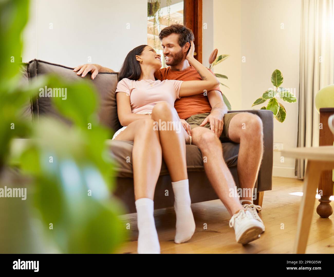 Happy, romance and couple relax indoors together, bonding and talking on sofa together. Young husband and wife sharing intimate moment, enjoying conversation, relationship and freedom at home Stock Photo