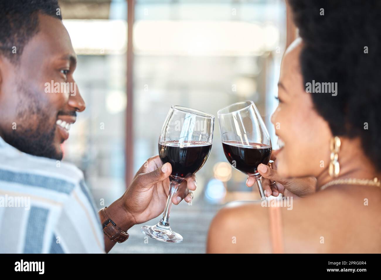 Couple giving cheers, toast and celebrate with wine glass, champagne and alcohol drinks on a romantic date together. Love, relax and smile black people in celebration of happy marriage relationship Stock Photo