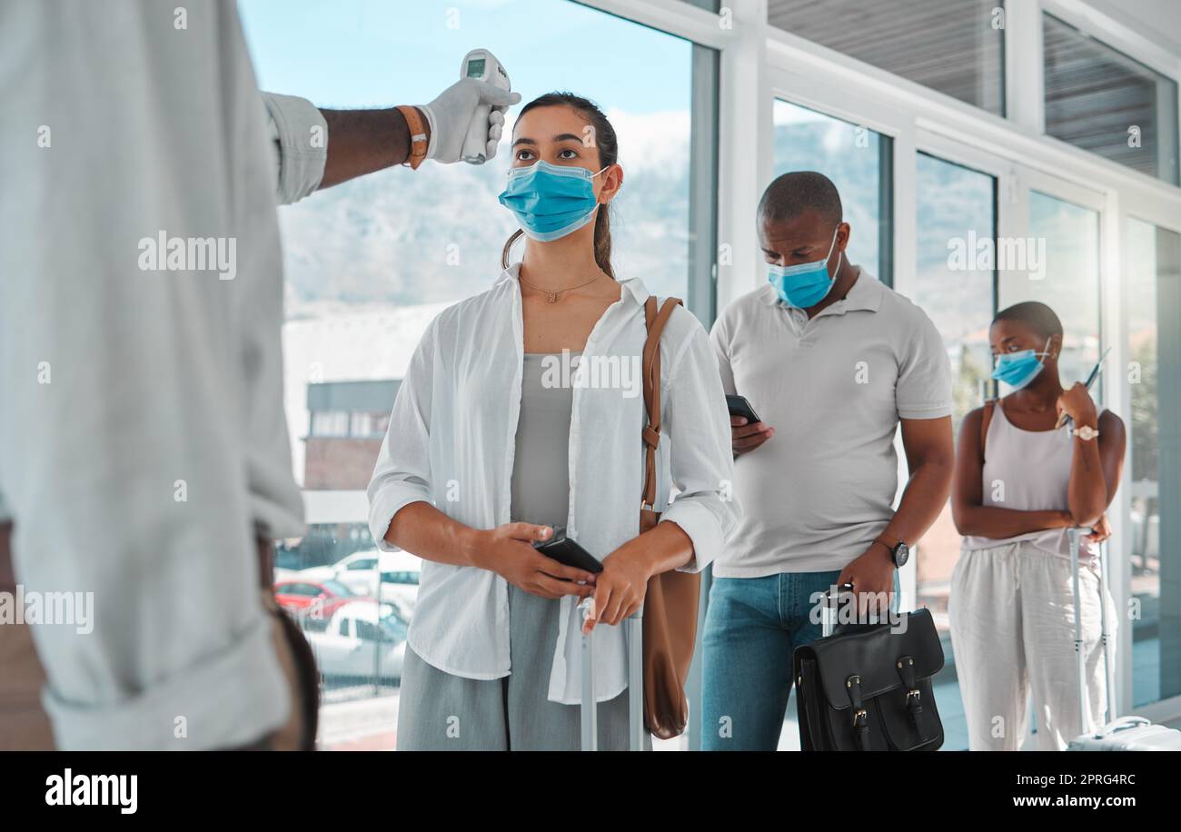 Covid safety traveling, medical doctor with thermometer testing and screening or healthcare doing protocol checkup of people at airport. Travel nurse worker scanning during the corona virus pandemic Stock Photo