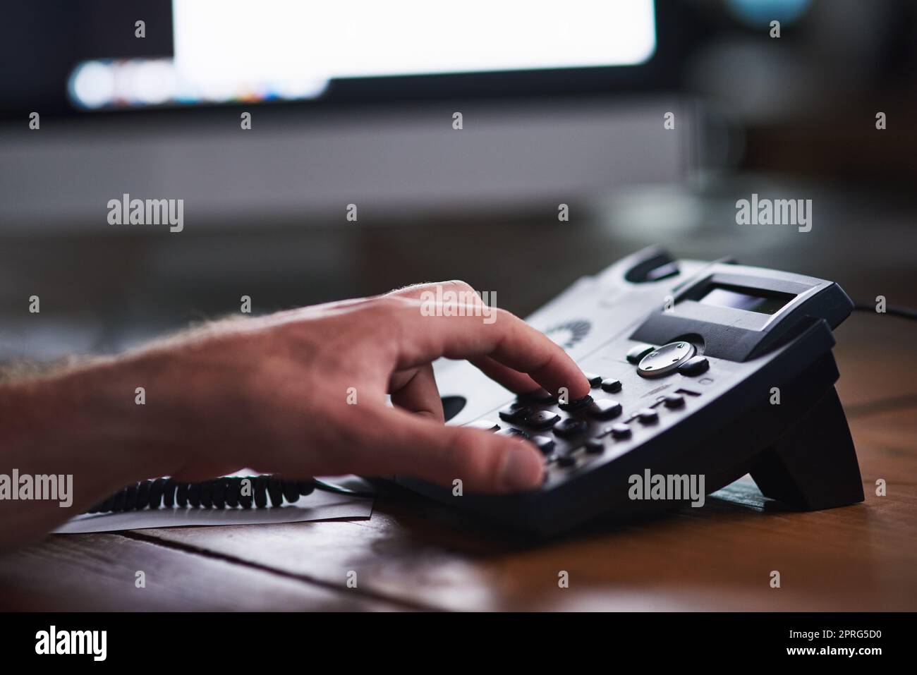 Closeup of a corporate business man making a telephone call to a colleague, partner or client. A company employee, male executive or industry professional using a desk phone to contact a department Stock Photo