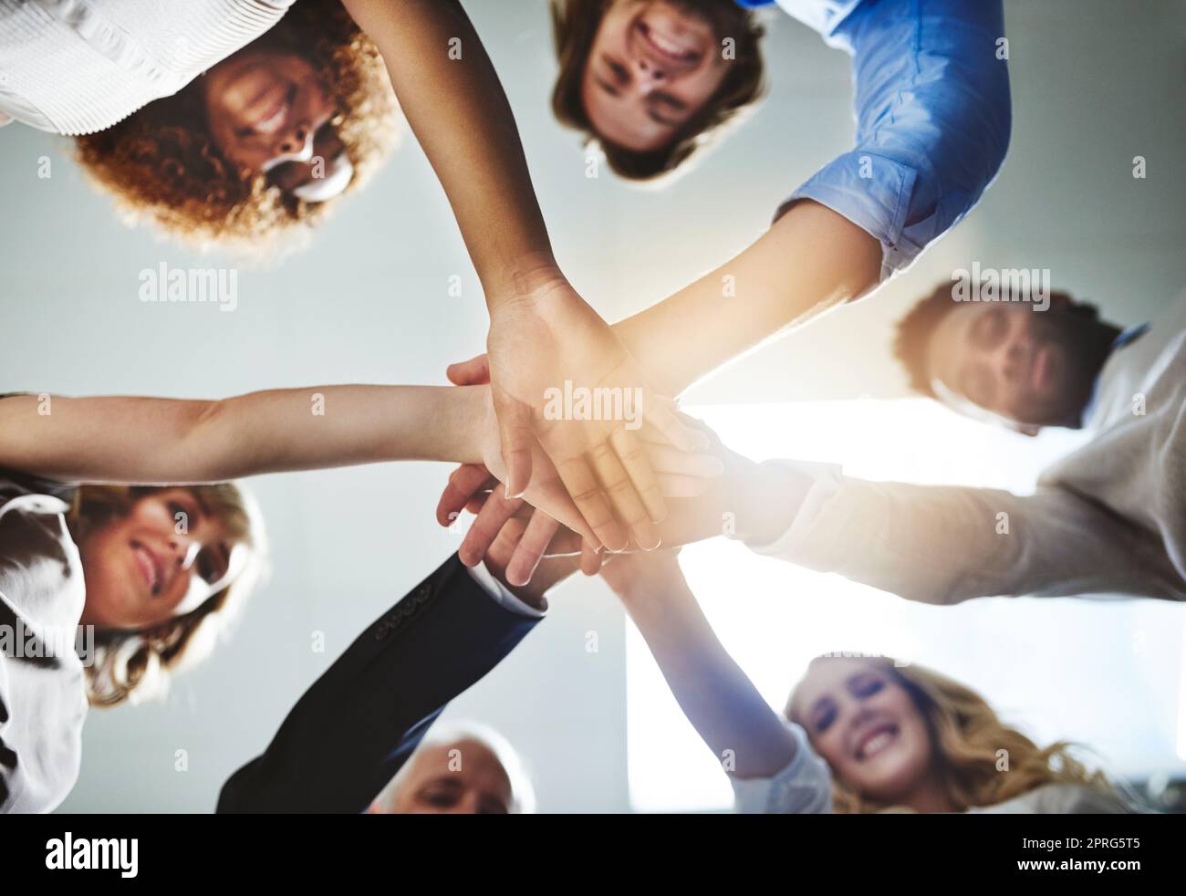 When we go all in we all win. Low angle shot of a group of colleagues joining their hands in solidarity. Stock Photo