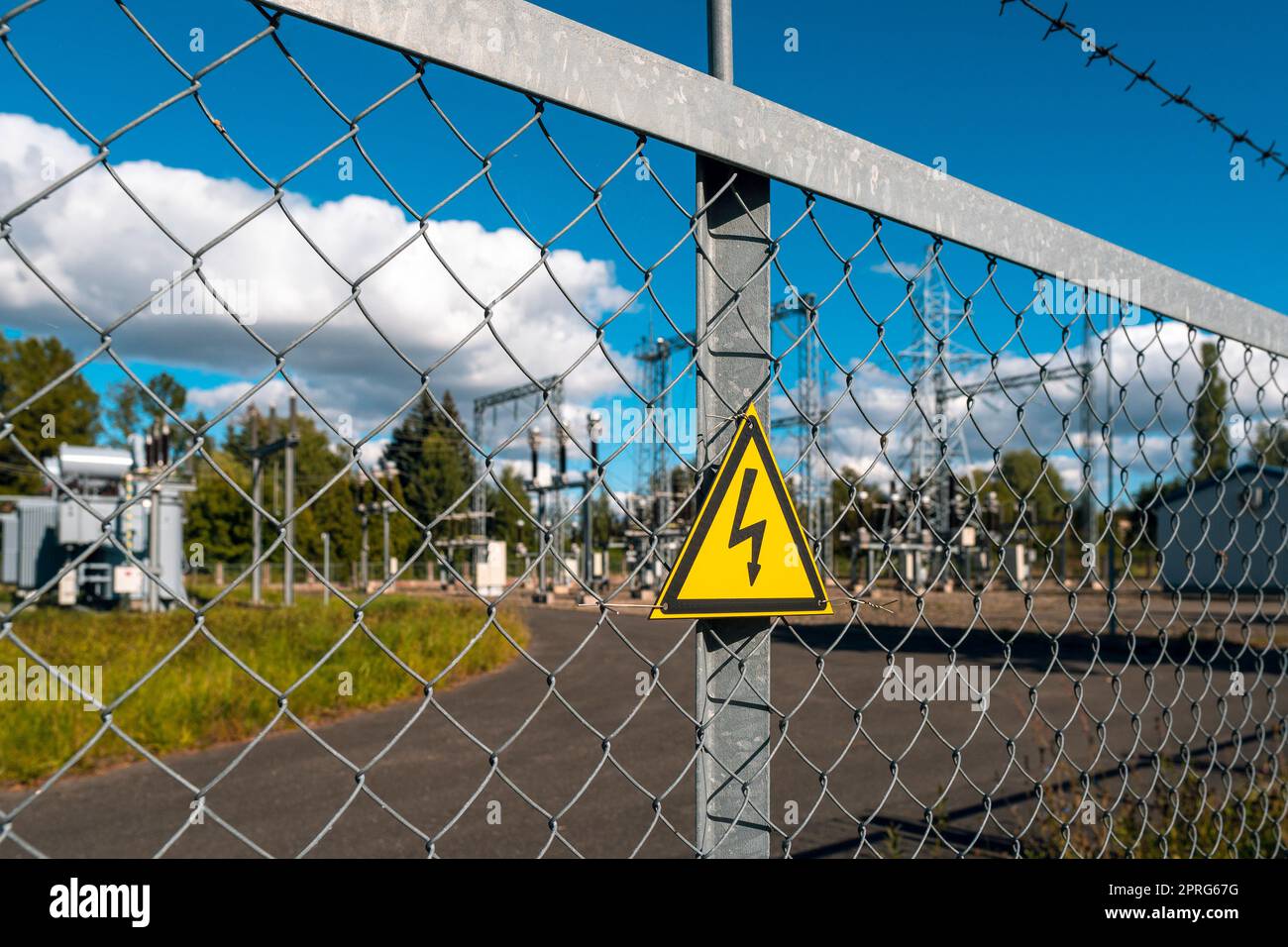 Yellow triangle with lightning behind metal mesh fence Stock Photo