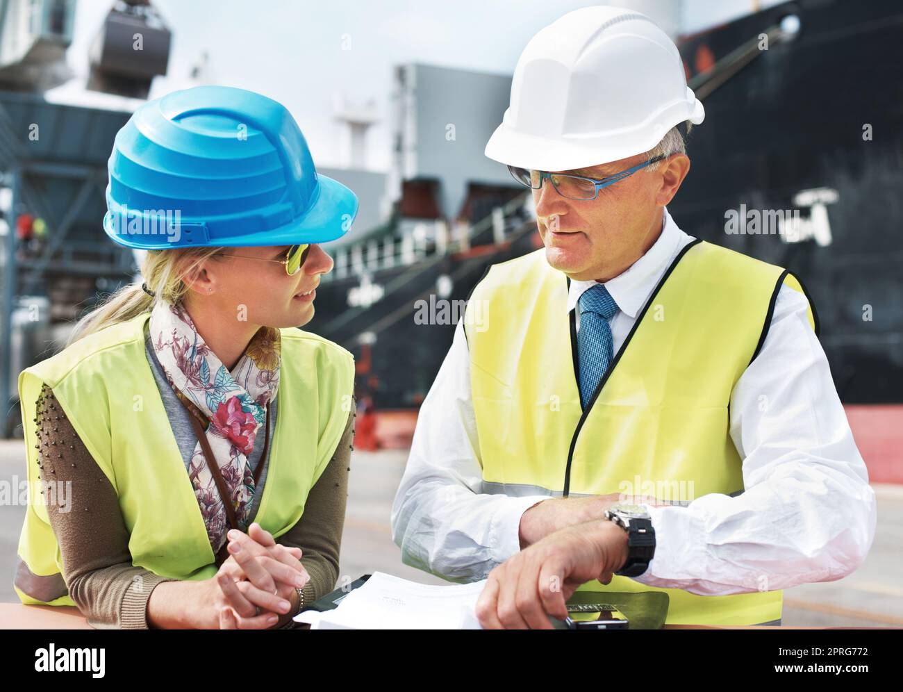 Dock worker, shipping and cargo delivery industry workers in safety gear working on logistics papers of the transportation. Supply chain, administration and managers in collaboration and conversation Stock Photo