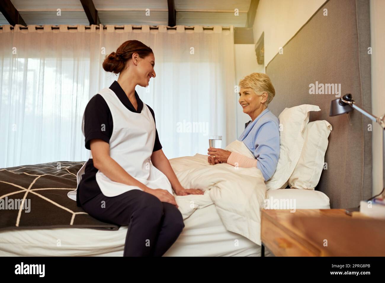 And how are you feeling today. a nurse sitting with her elderly patient in her room. Stock Photo