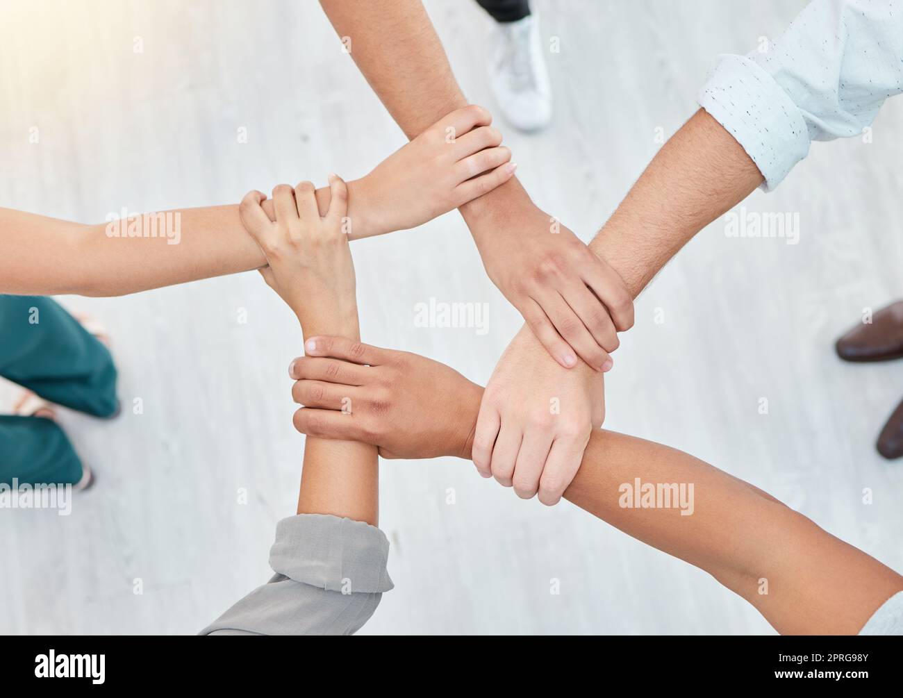 Hope, partnership and support group holding each other at community therapy session. Top view of people doing motivation, love and trust exercise while building a connection at mental health clinic. Stock Photo