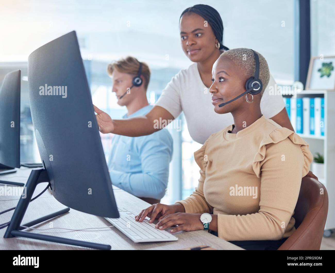 Call center manager coaching sales consultant, telemarketing employee and crm customer service worker with computer software in office agency. Mentor training woman with pc tech solution and strategy Stock Photo