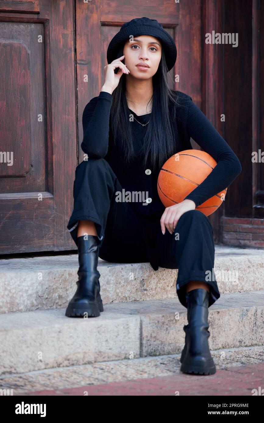 Fashion model, influencer and young woman with basketball posing on steps in urban city. Portrait of trendy, stylish and cool person with funky attitude, grunge personality and modern black clothes Stock Photo