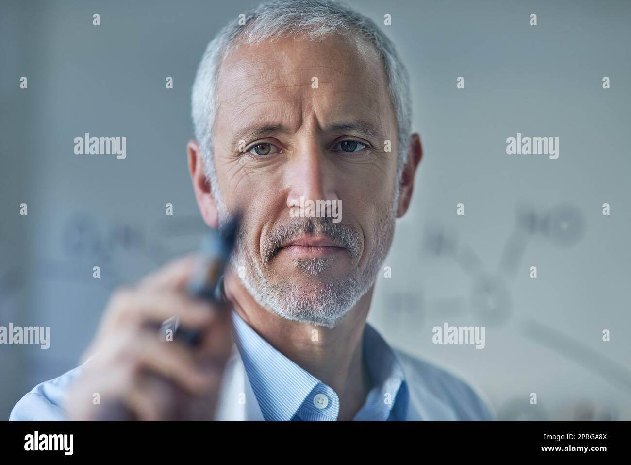 Testing his formulae. a male scientist drawing molecular structures on a glass wall in a lab. Stock Photo