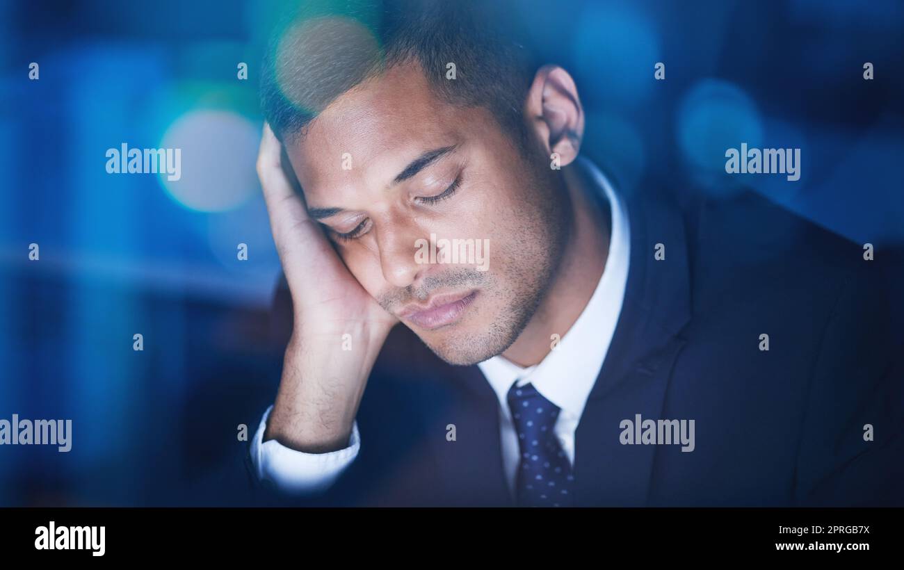 Tired, overworked and exhausted businessman sleeping while working overtime in the office at night. Fatigue, burnout and lazy corporate manager sitting at desk and taking nap in the company building. Stock Photo