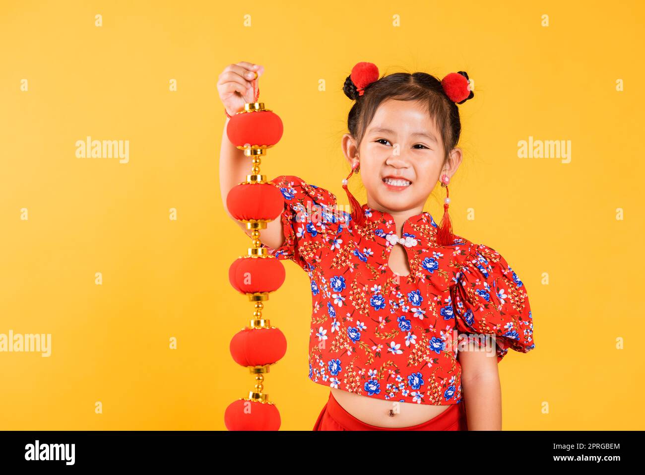 Happy Asian Chinese little girl smile wearing red cheongsam qipao holding silk lanterns Stock Photo
