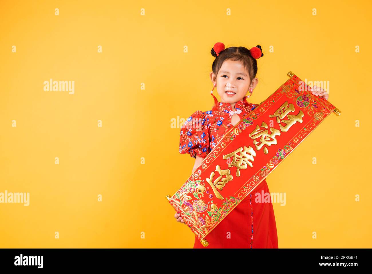 Happy Asian Chinese little child girl smile wearing red cheongsam qipao Spring festival couplets Stock Photo