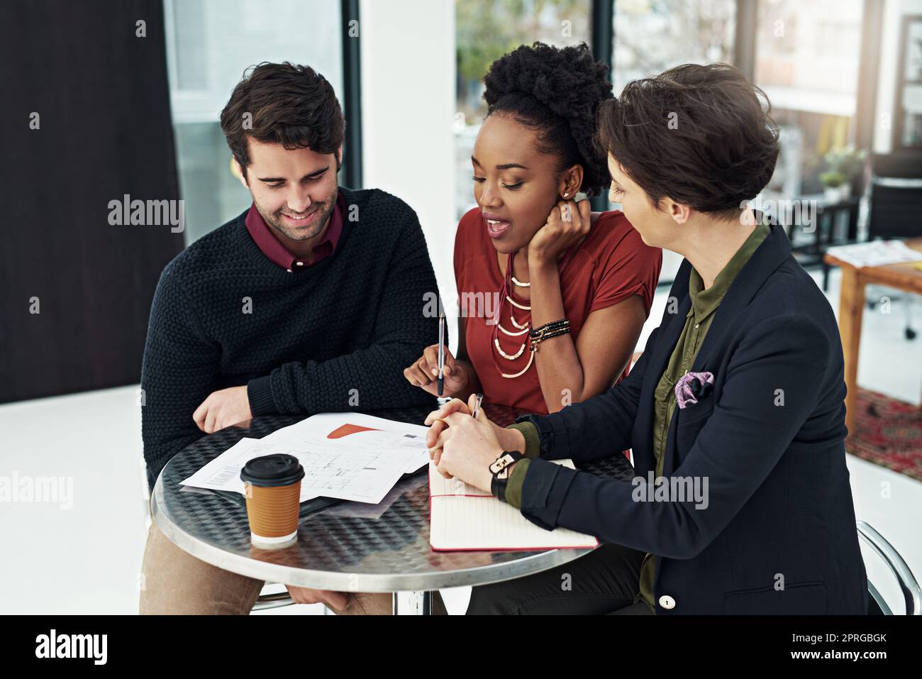 The skys the limit for this team. a group of businesspeople meeting around a small table in their office. Stock Photo