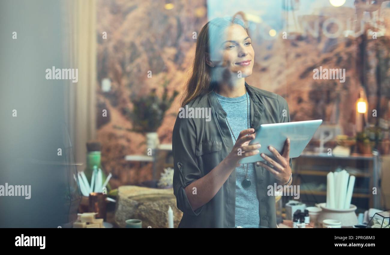 Managing her store online. a young woman using a tablet indoors. Stock Photo