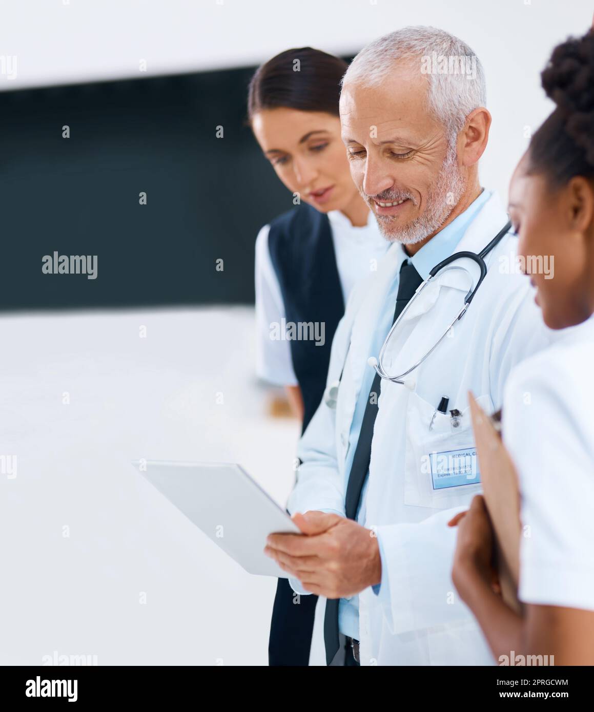 Im impressed with the treatment you chose. a group of medical professionals discussing something on a digital tablet. Stock Photo
