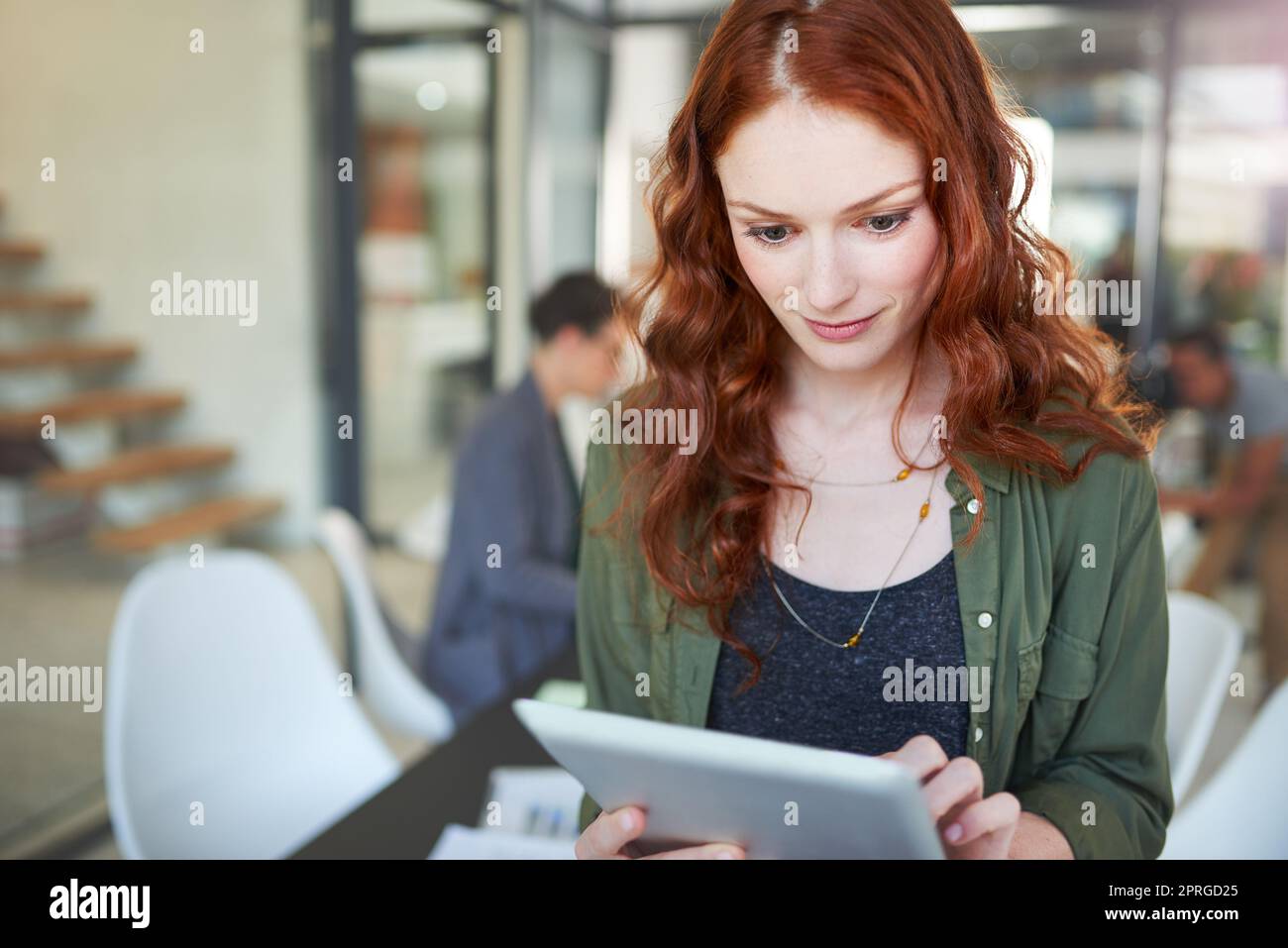 Checking her schedule for the rest of the day. a young creative working on a digital tablet in a modern office. Stock Photo